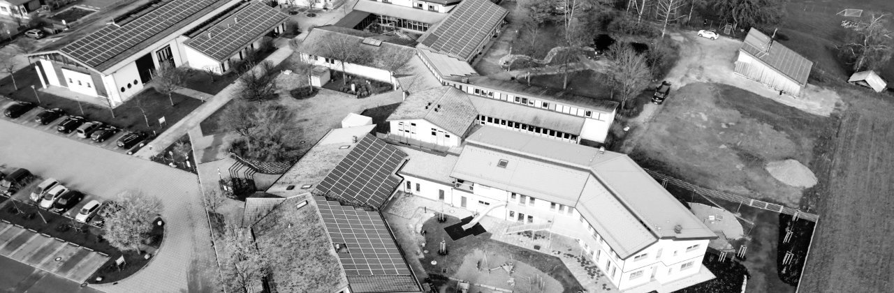 Luftaufnahme der Grundschule mit Sportgelände und Heizhaus in Eurasburg (Schwaben) in schwarz-weiß