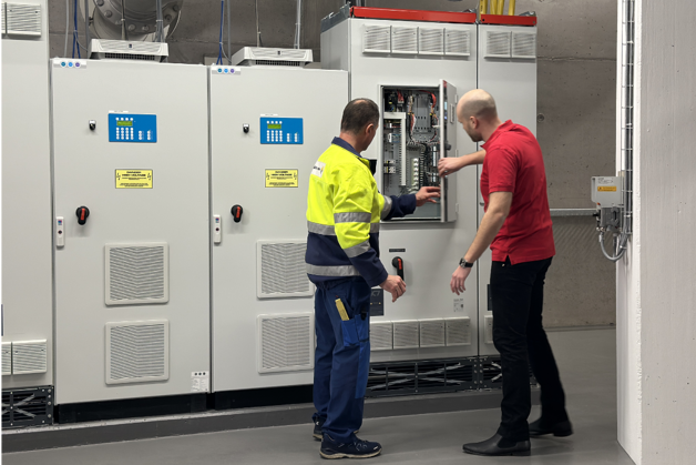 Michael Mühlethaler de la Gebrüder Meier, partenerul Danfoss pentru lucrări de service, și Jesper Christensen, manager partener Danfoss, arată cât de ușor se pun în funcțiune și se întrețin convertizoarele de frecvență iC7.