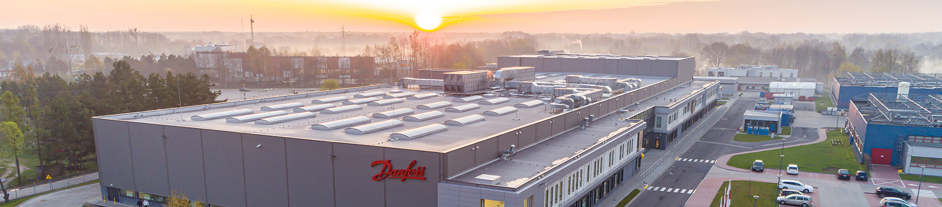 Die Fabrik aus der Ferne gesehen mit einem Sonnenaufgang im Hintergrund