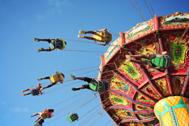 Personas en un tiovivo de sillas altas en una feria